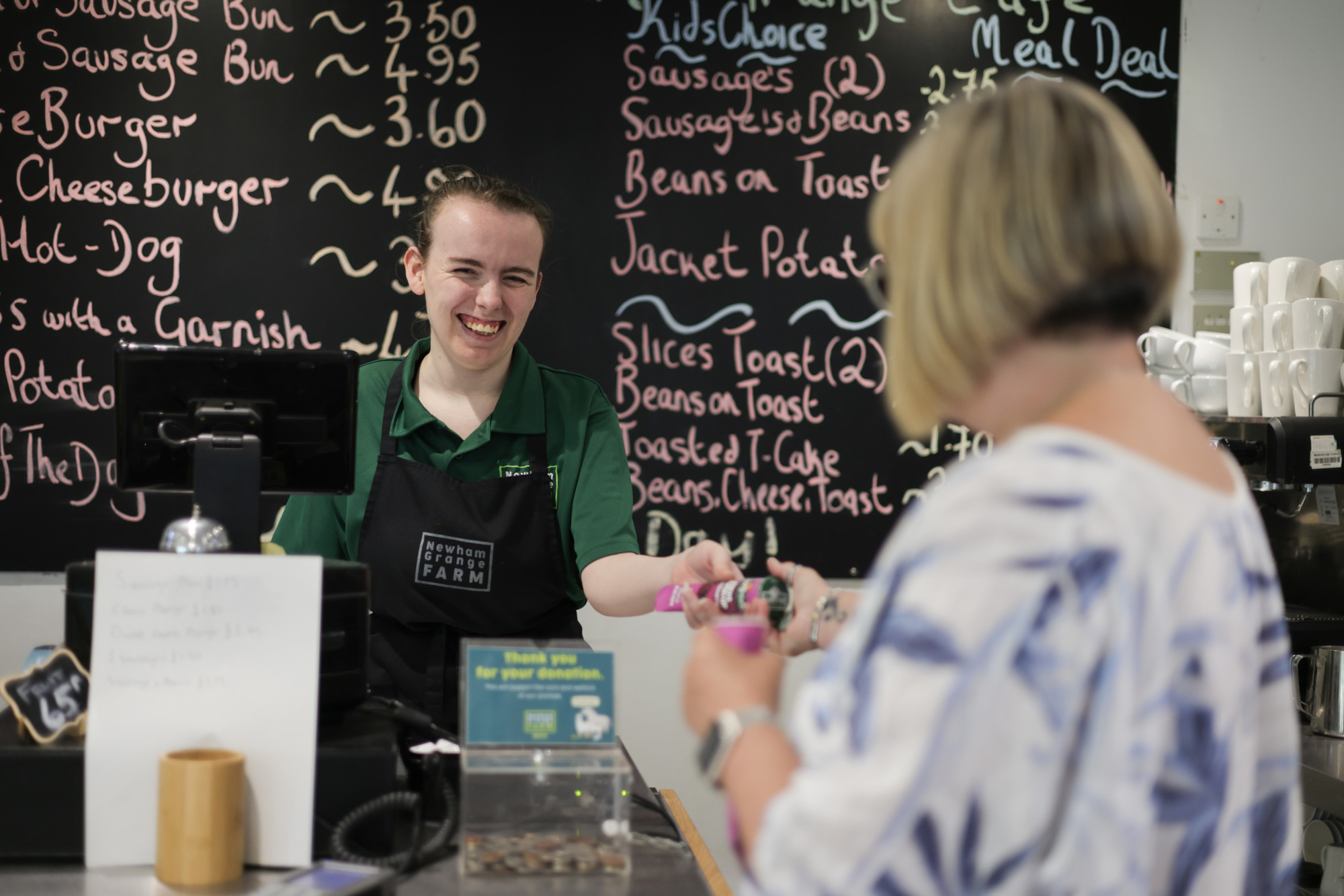Ordering some tasty snacks at the cafe at Newham Grange in front of a blackboard of specials